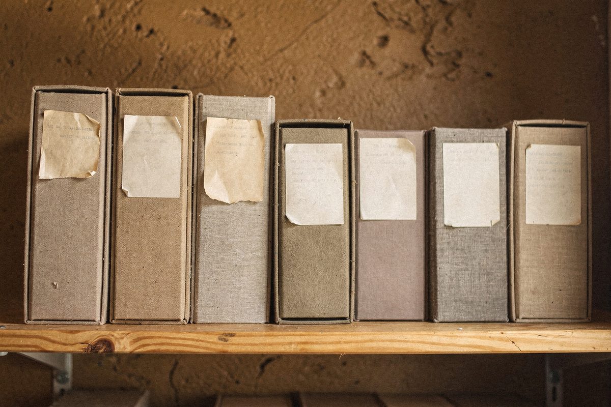 A shelf of cloth-bound archive boxes and binders from past studio projects.