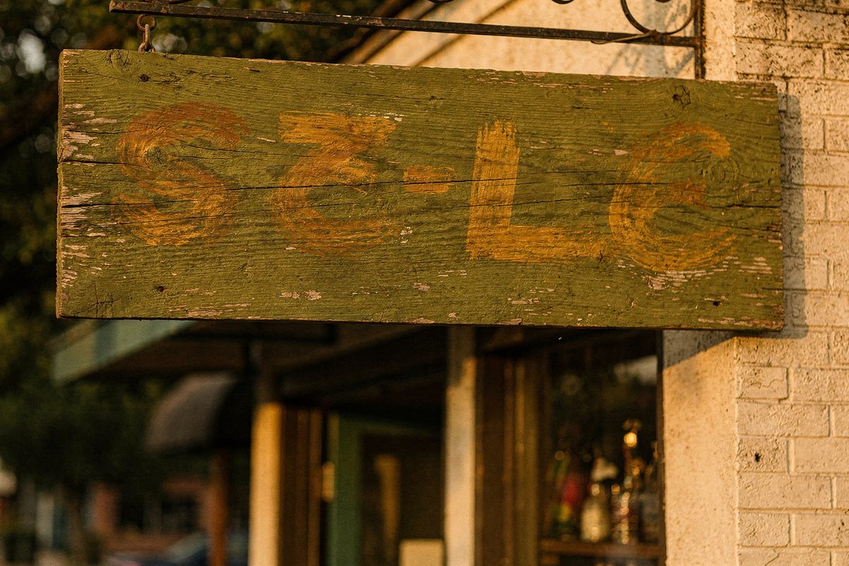A finished hand-painted wooden trade sign mounted above a shop entrance.
